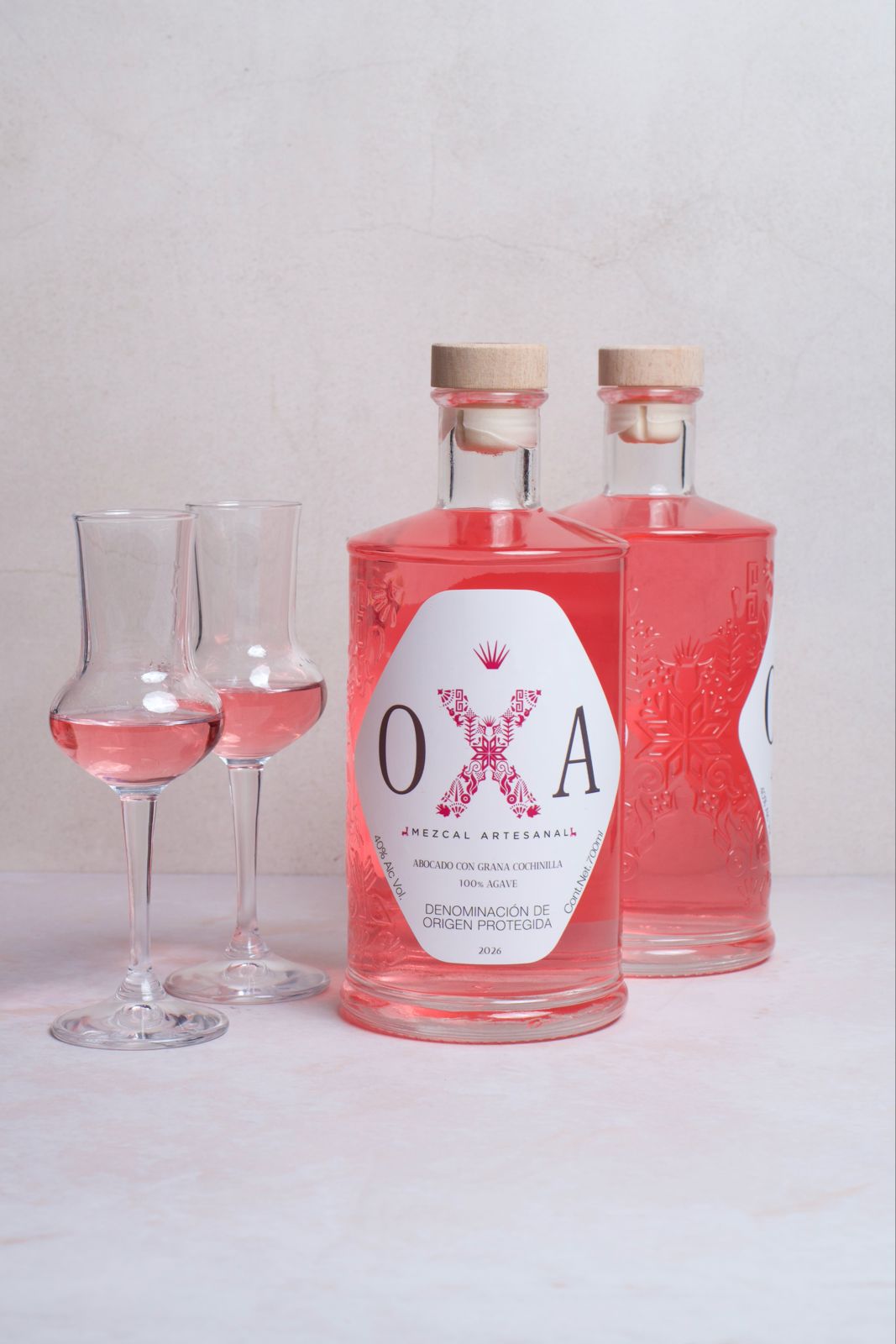 Botella de OXA Rosa con dos copas de cristal fino servidas.