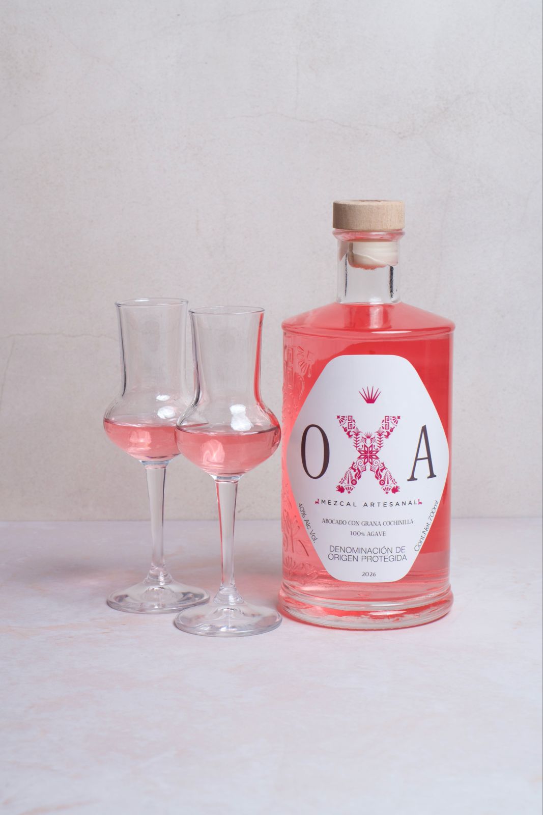 La copa OXA servida junto a la botella de OXA Rosa.